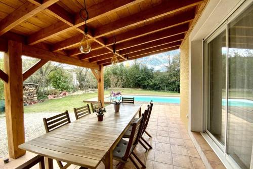- une table en bois sur la terrasse d'une maison dans l'établissement GROOMI La Gardoise- Villa swimming pool and pétanque court!, à Moulézan