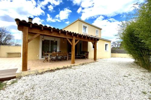 une maison avec une pergola en bois sur une terrasse dans l'établissement GROOMI La Gardoise- Villa swimming pool and pétanque court!, à Moulézan