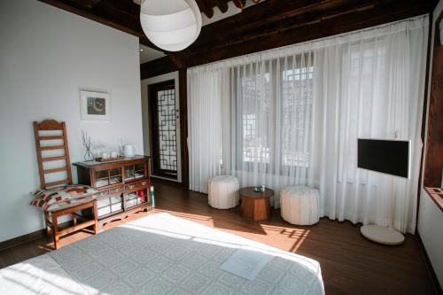 a bedroom with a bed and a television and a chair at Hanok Stay SungHyeDang in Gyeongju