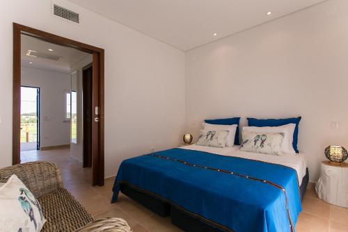 a bedroom with a blue bed and a chair at Casas Do Rio Sado - Sado River Country Retreat in Santa Margarida do Sado