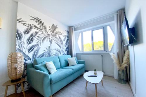 a blue couch in a living room with a palm mural at Lensoleillée - Proche port et climatisé ! in Mauguio
