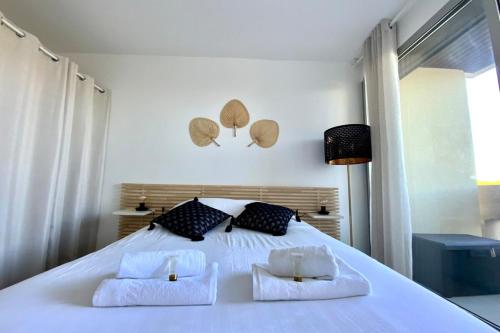 a bedroom with a large white bed with two pillows at Lensoleillée - Proche port et climatisé ! in Mauguio