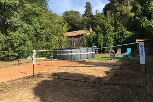 una pista de tenis con red en una pista en La Bucolique-Villa in the heart of greenery! en Saint-Jean-de-Védas