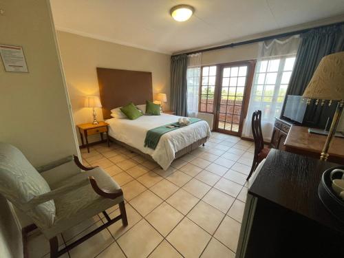 ein Schlafzimmer mit einem Bett, einem Stuhl und einem TV in der Unterkunft Edelweiss Corporate Guest House in Pretoria
