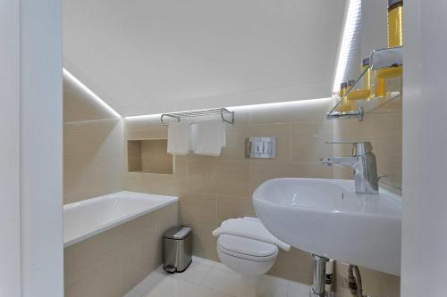 a white bathroom with a sink and a toilet at Cleveland Residences Russell Square in London