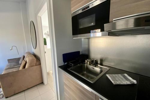 une petite cuisine avec un évier et un micro-ondes dans l'établissement Le fonctionnel - Grande terrasse en plein centre !, à Castelnau-le-Lez