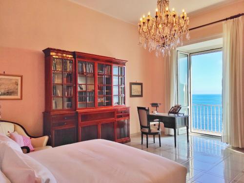 um quarto com uma cama, uma secretária e um lustre em Villa Don Guglielmo AMALFI COAST em Ravello