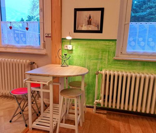 a table and stools in a room with a green wall at Ferienwohnung Gransee unmittelbar am Stechlinsee - Radweg 
