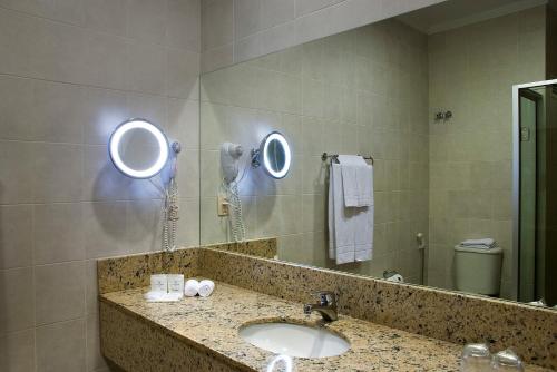 a bathroom with a sink and two mirrors at Master Gramado Hotel - Espaço Kids Incrível in Gramado