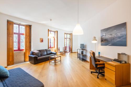 een woonkamer met een bank en een bureau bij Casa Trindade Apartments in Porto