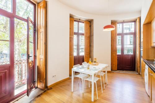 een eetkamer met een witte tafel en een aantal ramen bij Casa Trindade Apartments in Porto