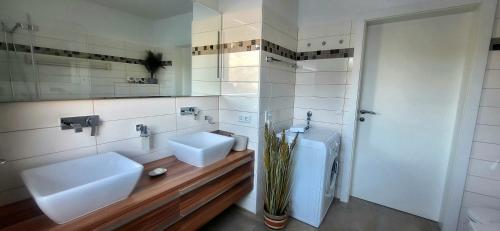 een badkamer met 2 witte wastafels en een spiegel bij Dachsteinblick by Alpendyll Apartments in Haus im Ennstal