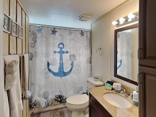 a bathroom with a shower with an anchor shower curtain at Flip Flop Beachside in Galveston