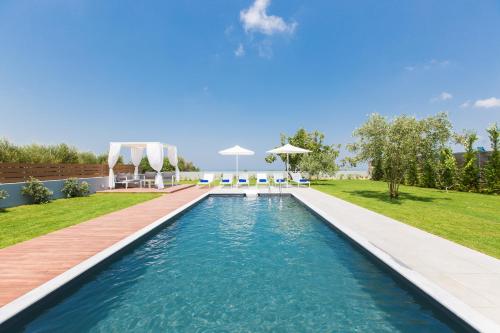 una piscina en un patio trasero con terraza y césped en Vilana Exclusive Villas, en Skouloúfia
