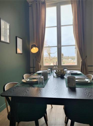 une table de salle à manger avec des chaises et une grande fenêtre dans l'établissement Le Gatsby, à Chartres