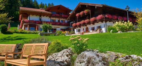 a house with two chairs in front of it at Alpenhotel Hundsreitlehen in Bischofswiesen