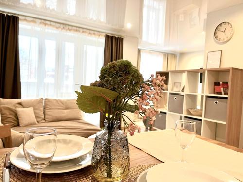una sala de estar con una mesa con gafas y un jarrón con flores en Modern Charming Studio Narva Center en Narva