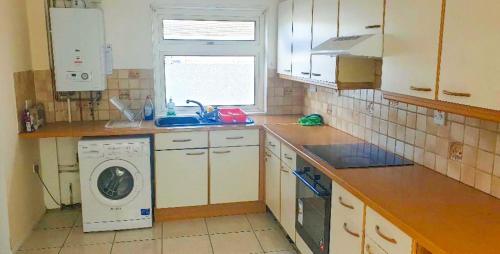 a kitchen with a washing machine and a sink at Cosy Single Room in Redditch: Free Parking/Wi-fi in Headless Cross