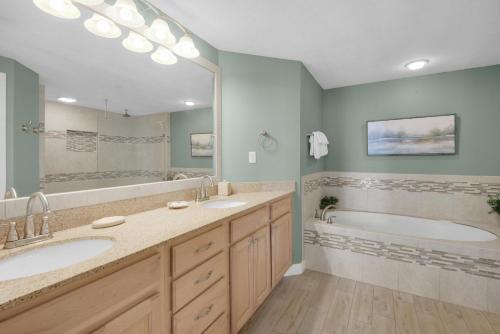 a bathroom with two sinks and a tub and a large mirror at Grandview East 1204 in Panama City Beach
