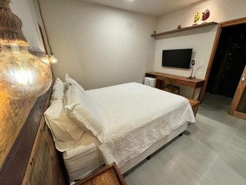 a bedroom with a white bed and a television at POUSADA PONTA DA ASA in Coruripe