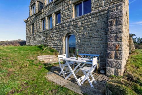 a table and chairs on a deck outside of a stone building at Studio vue sur mer in Plomodiern