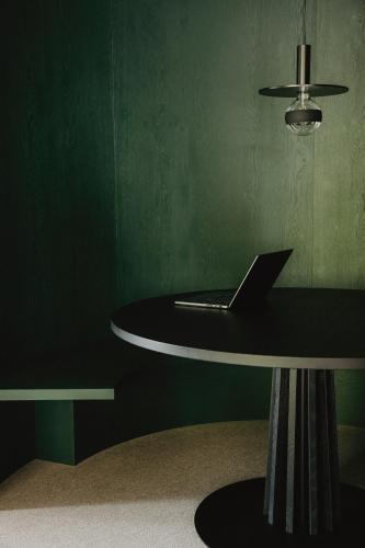 a table with a laptop on it in a green room at AMA Stay in San Vigilio Di Marebbe