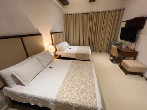 a hotel room with two beds and a television at Hotel Dorado Plaza Centro Histórico in Cartagena de Indias