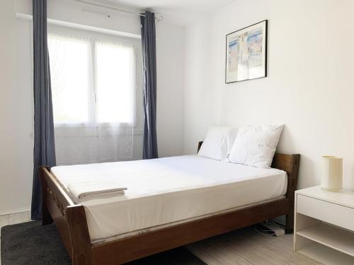 een slaapkamer met een bed met witte lakens en een raam bij Le Mainvillois - Parking Included in Mainvilliers
