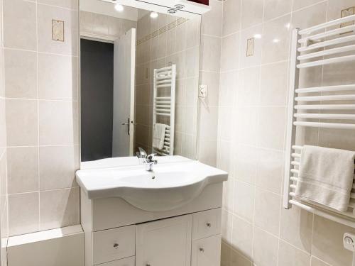 a white bathroom with a sink and a mirror at Le Mainvillois - Parking Included in Mainvilliers