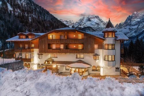 a large house in the mountains with snow around it at Bio Hotel Hermitage in Madonna di Campiglio