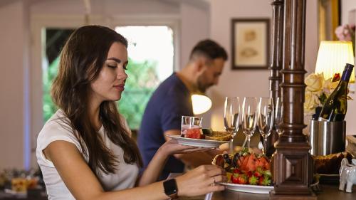 a woman holding a plate of food and wine glasses at penzion Dvorce in Třeboň