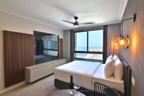 a bedroom with a bed and a window and a table at Luxury Suites by Notaly Ariel - Carmel Beach in Haifa
