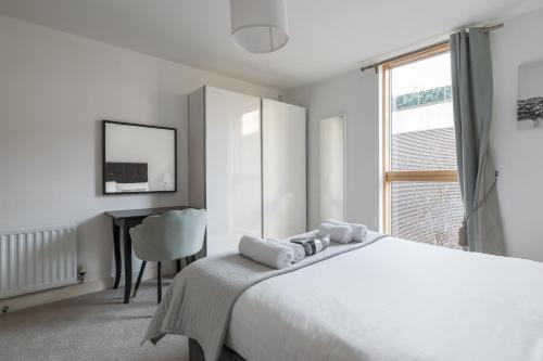 a white bedroom with a bed and a desk at City Stay Apartments - Vizion in Milton Keynes