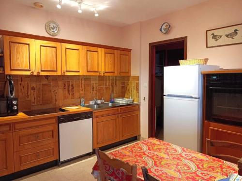 une cuisine avec des armoires en bois et un réfrigérateur blanc dans l'établissement Appartement avec Terrasse, WIFI, Animaux admis, Parking à Trégastel - FR-1-368-209, à Trégastel
