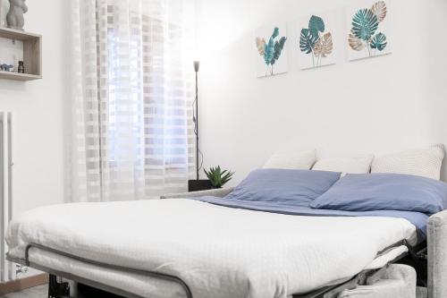Ca' Latina - Cozy home in pieno centro storico في تريفيزو: غرفة نوم بيضاء مع سرير ووسائد زرقاء