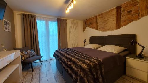 a bedroom with a bed and a chair and a window at Pension Holl und Boll Am Hexenstieg. in Clausthal-Zellerfeld