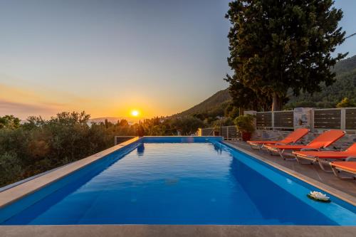 a pool with chairs and the sunset in the background at Villa Ameli in Neo Klima