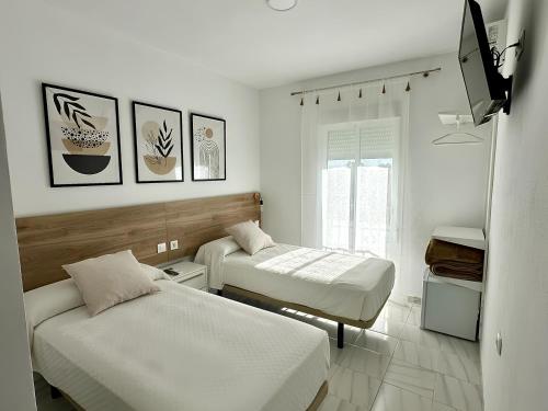 a room with two beds and a tv on the wall at Hostal Merino Jédula in Jedula