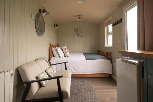1 dormitorio con 1 cama y 1 silla en Shepherds Hut near Gortin Omagh, en Omagh