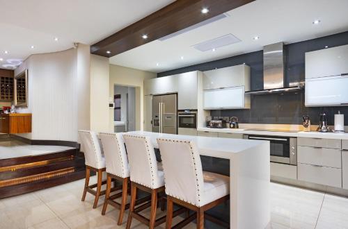 a kitchen with white chairs and a white counter at Baronetcy Kings Villa by Host Agents in Plattekloof
