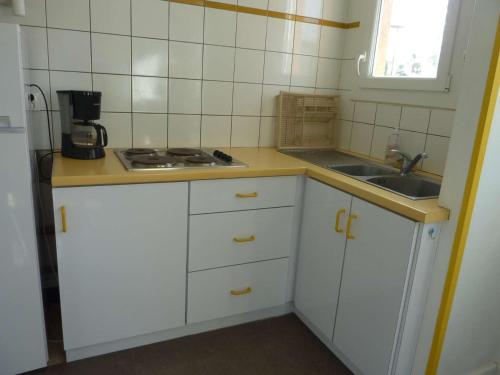 une petite cuisine avec des armoires blanches et un évier dans l'établissement Marseillan Plage : Appartement 6 pers avec Terrasse, Parking et Option Internet - FR-1-387-159, à Marseillan