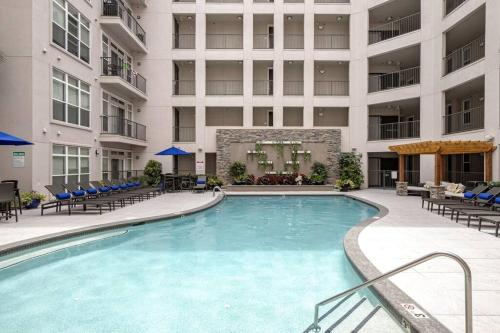 a swimming pool in a hotel with chairs and a building at League Flats South End on South College Street in Charlotte