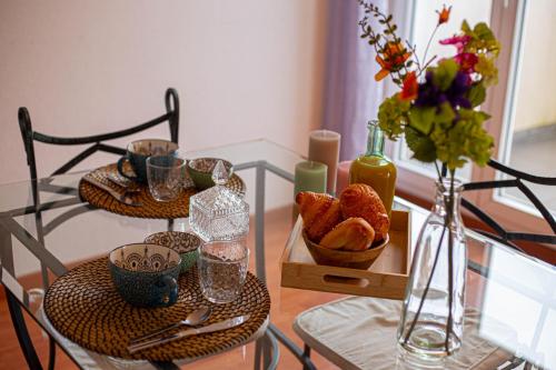 einen Glastisch mit einem Tablett Brot und einer Vase Blumen in der Unterkunft City Break Picquecailloux in Bordeaux