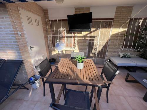 una mesa de madera y sillas en una habitación con TV en Apartamento con terraza en San Juan Playa, en Alicante