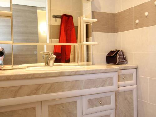 La salle de bains est pourvue d'un lavabo et d'un peignoir rouge. dans l'établissement T2 rénové avec jardin et parking, proche Thermes, clim, wifi, lave-linge - FR-1-553-54, à Balaruc-les-Bains