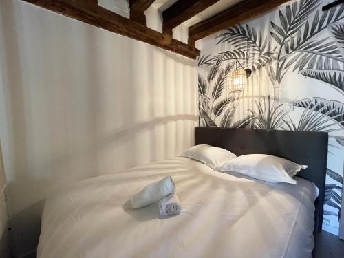a bedroom with a bed with white sheets and a plant wall at L'Eure Tranquille in Chartres