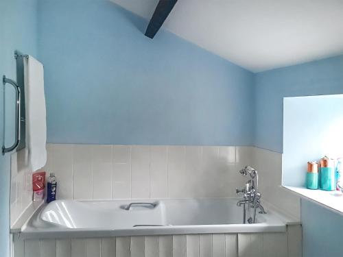a white bath tub in a bathroom with blue walls at Rose Cottage in Grinton