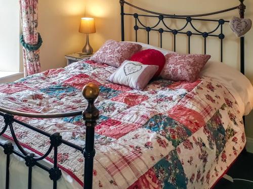 a bed with a quilt and pillows on it at Rose Cottage in Grinton