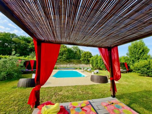 een tafel met rode gordijnen naast een zwembad bij MEUBLE PANORAMIQUE 2 à 6 PERSONNES AU CHÂTEAU DE JALLANGES in Vernou-sur-Brenne