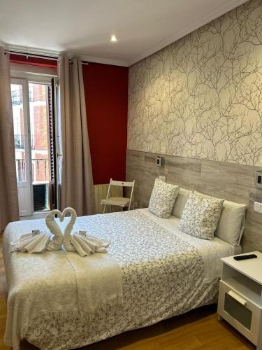 dos cisnes sentados en una cama en un dormitorio en Hostal New Dream Madrid en Madrid